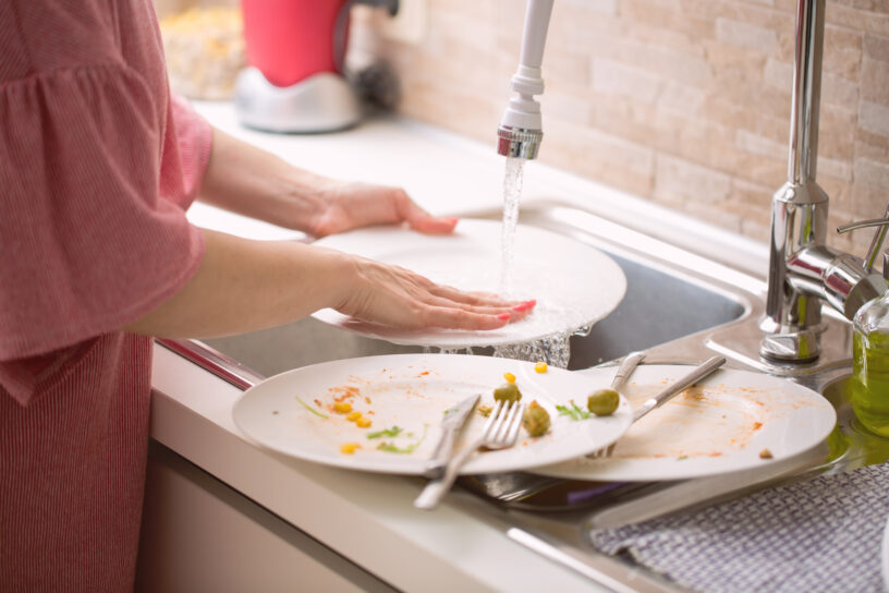 Young woman doing the dishwashing: washing a white plate under r